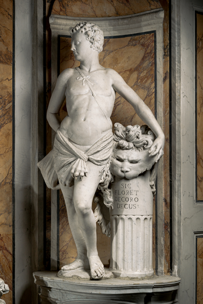 Statua del decoro - giovane avvolto da pelle di leone - parte della pelle di leone poggiata su una colonna - sulla colonna la scritta latina Sic Floret Decoro Decus